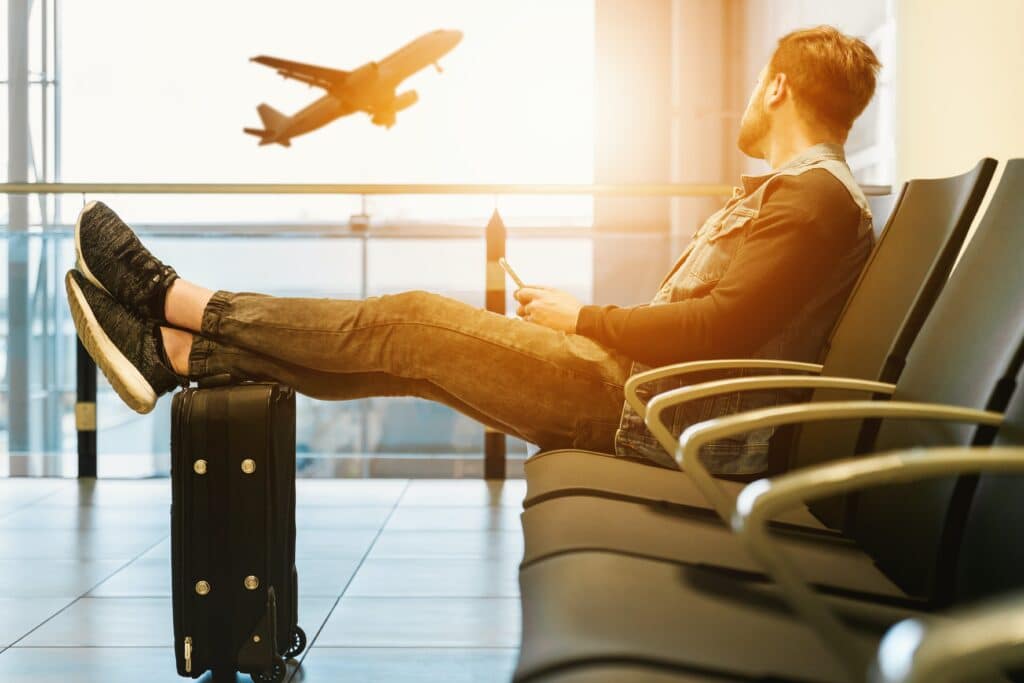 Man in airport waiting for boarding on plane. Sunshine Saturday flight hacks to get the best holiday deals.